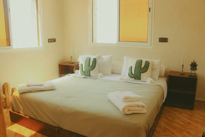 Bedroom with cactus-themed pillows and folded towels on the bed.